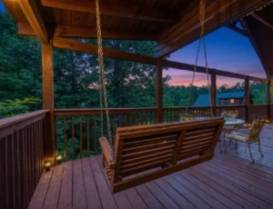 Rustic covered porch with wooden swing overlooking forested mountain sunset at best vacation rentals Gatlinburg