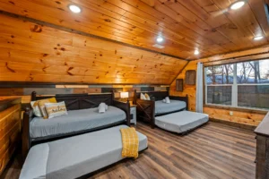 Rustic log cabin bedroom with multiple beds and mountain forest views in Gatlinburg TN