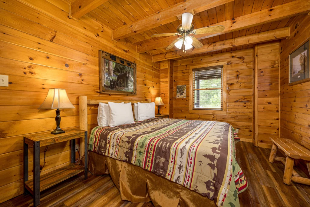 Cozy log cabin bedroom with knotty pine walls, queen bed, and rustic beams in Pigeon Forge TN