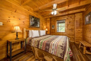 Cozy log cabin bedroom with knotty pine walls, queen bed, and rustic beams in Pigeon Forge TN