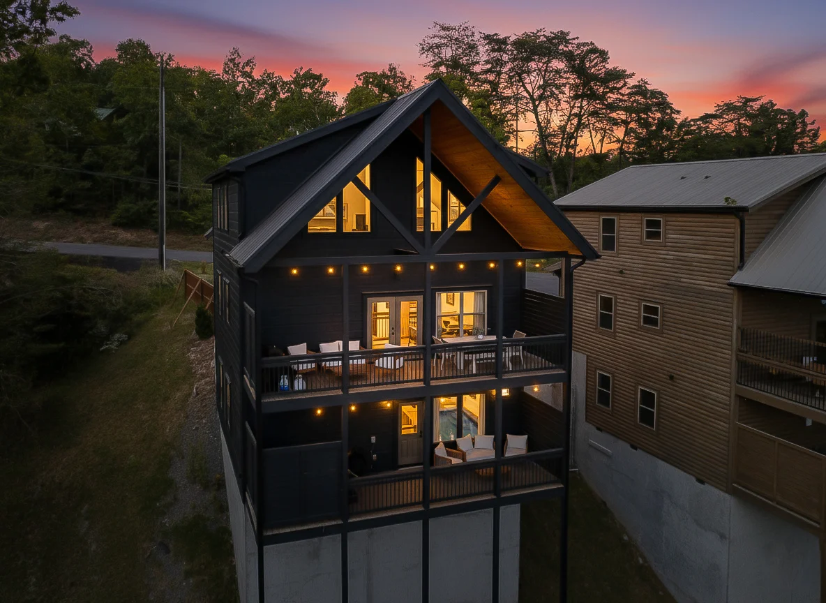 Modern black cabin with large windows and elevated deck at sunset, a short term rental in Pigeon Forge TN