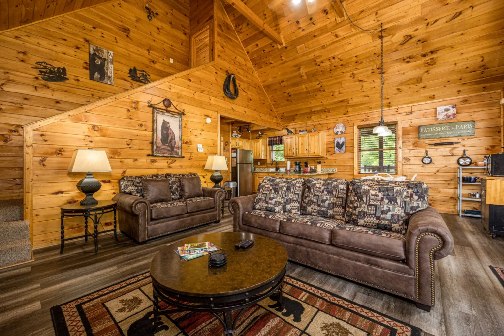 Spacious rustic log cabin living room with leather sofas and wildlife decor in a vacation rental by owner Gatlinburg TN area