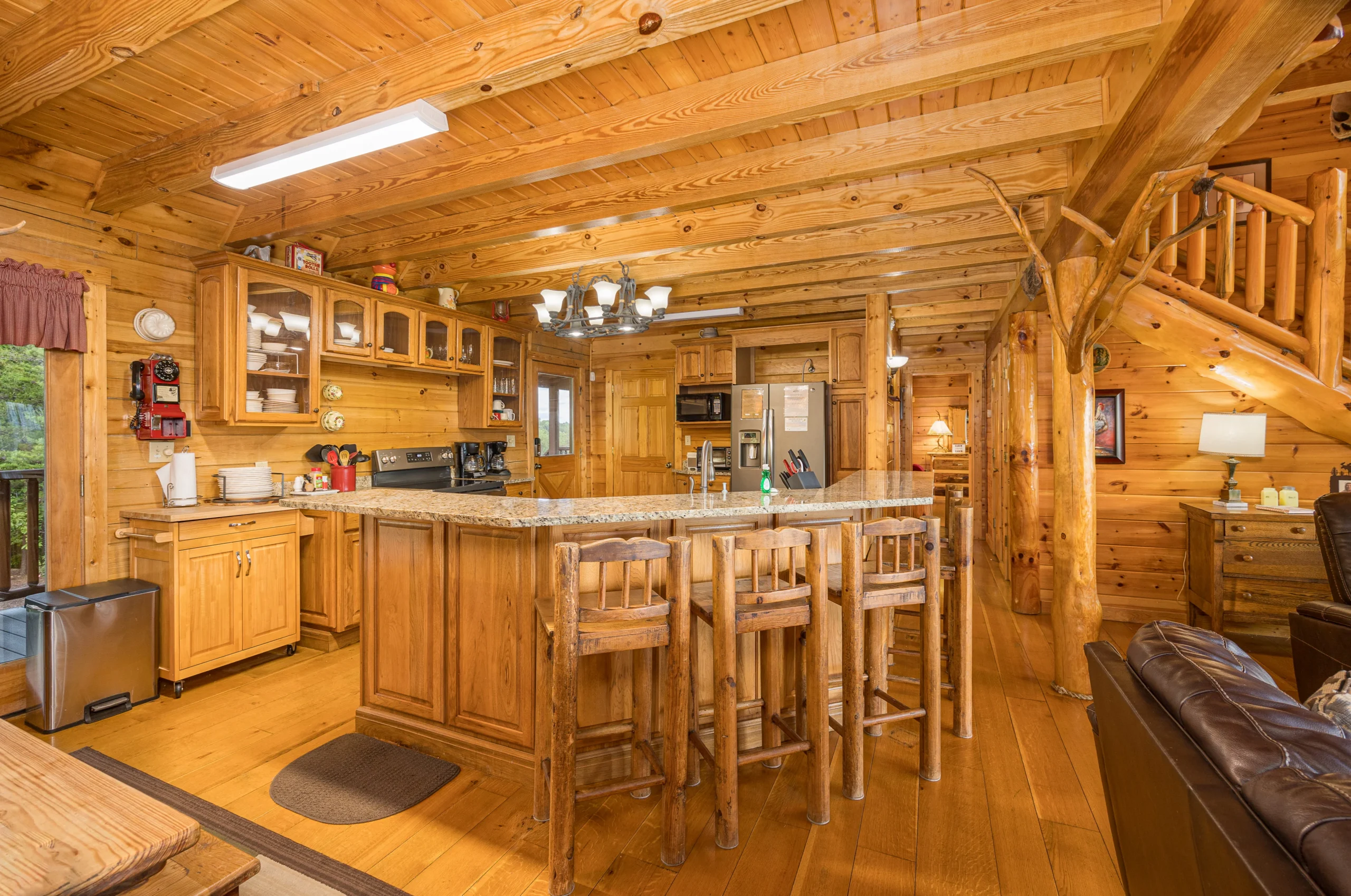 Spacious log cabin kitchen with granite island and covered deck views in Sevierville