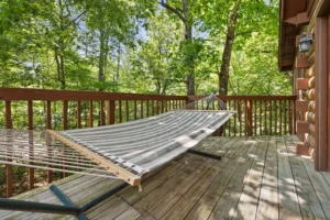 Striped hammock on wooden deck surrounded by forest trees in Sevierville cabin romantic getaway retreat