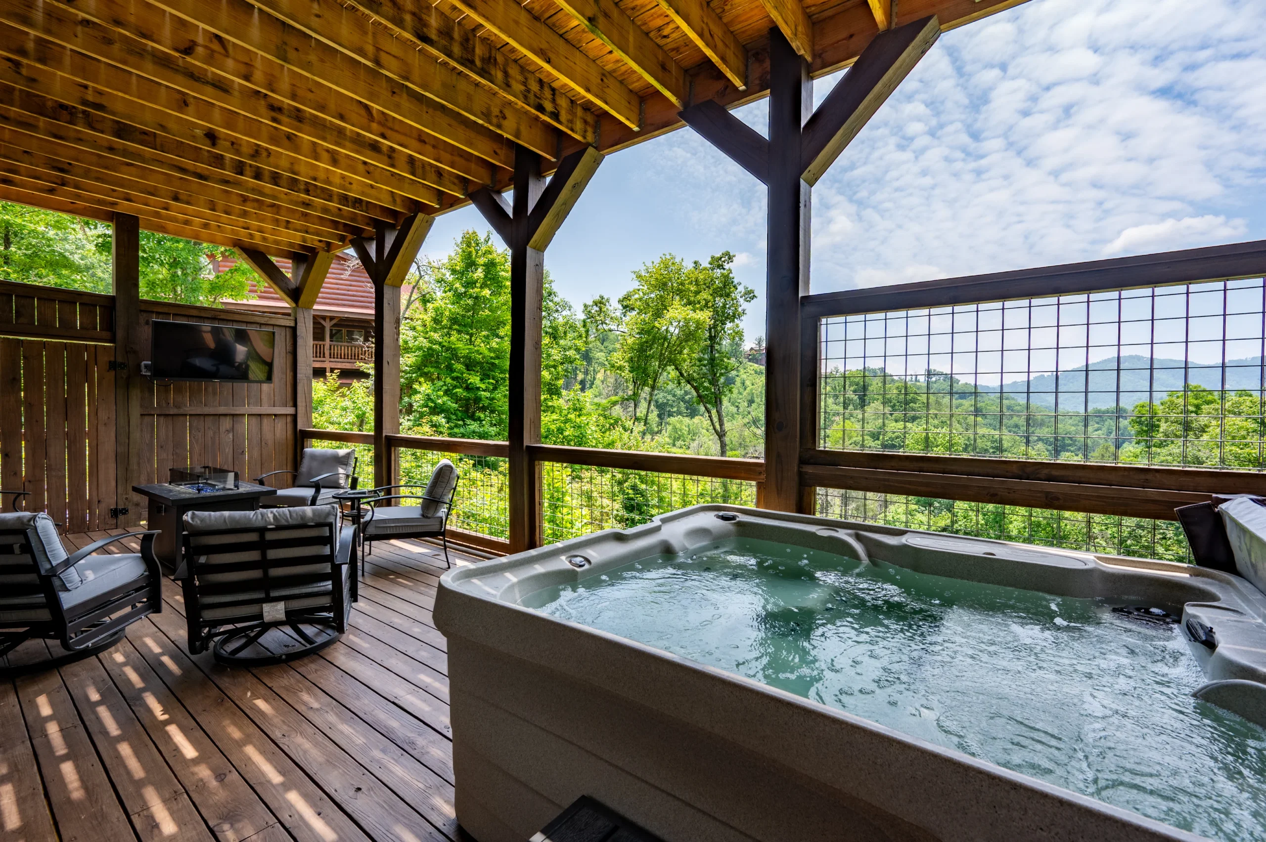 Luxury cabin deck with hot tub overlooking mountain and forest views at sunset in Sevierville TN