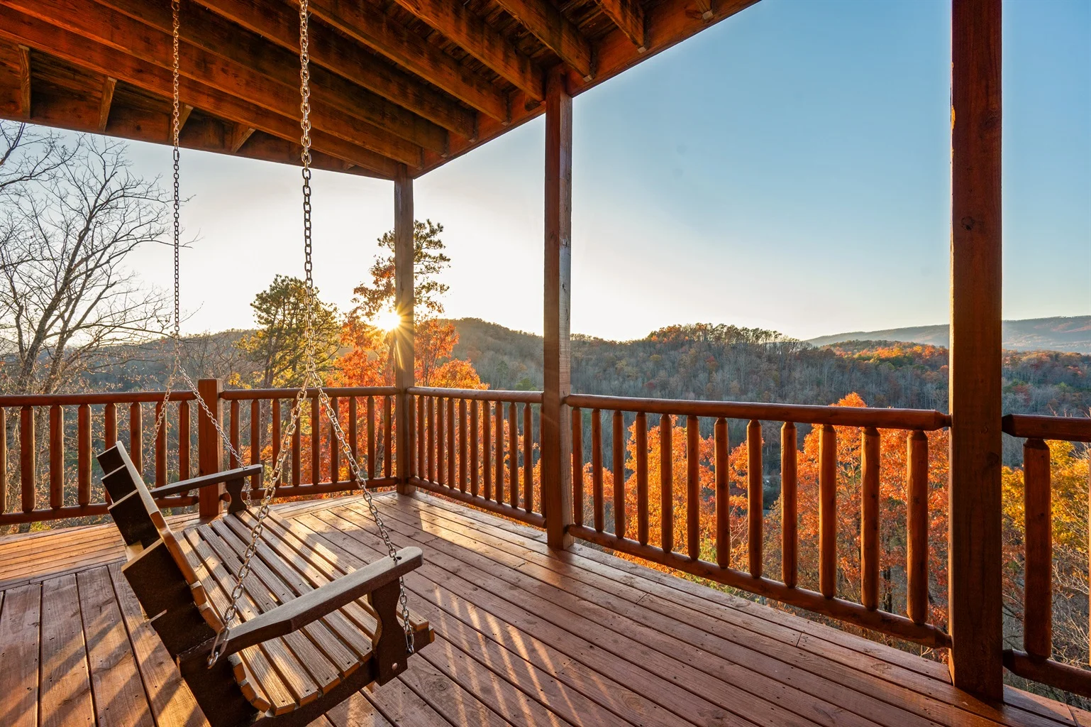 Covered porch with wooden swings overlooking autumn mountain views in a Sevierville vacation rental