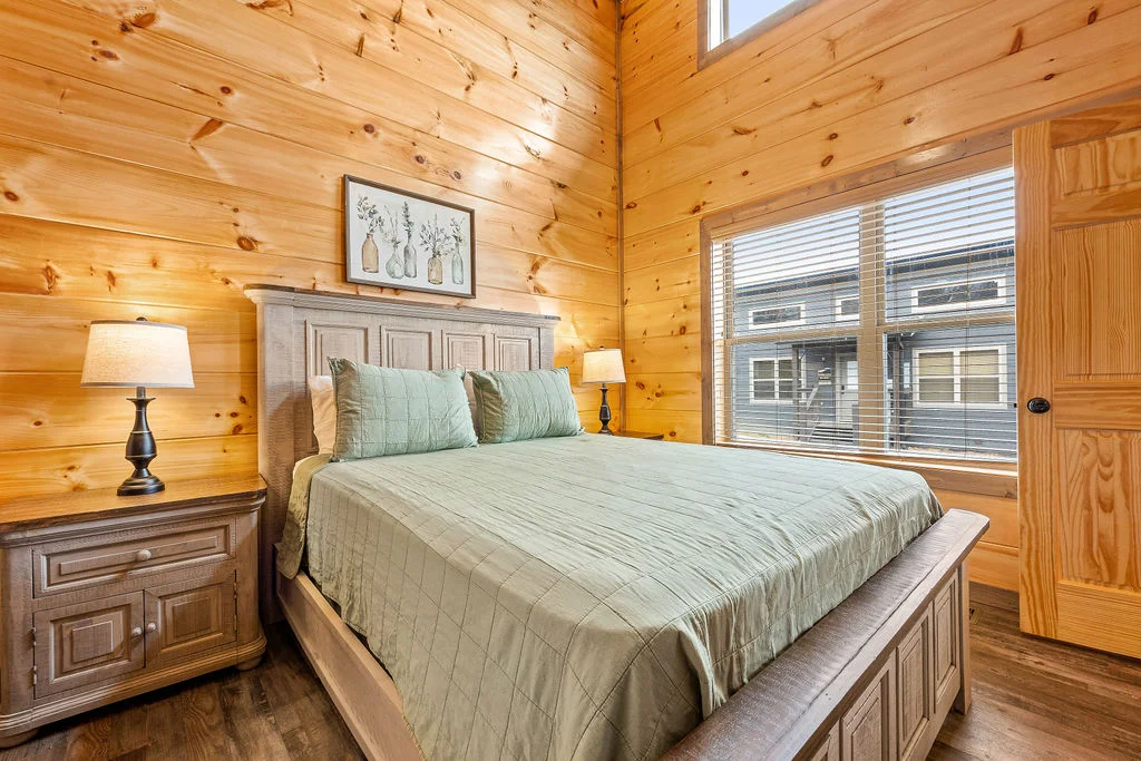 Log cabin bedroom with queen bed and wood paneling in Sevierville, TN
