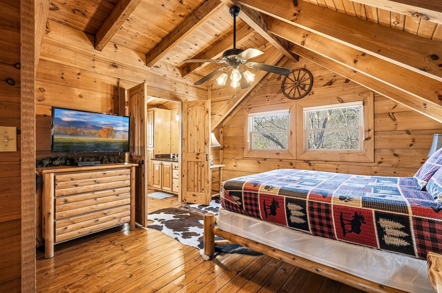 Log cabin bedroom with wooden beams, queen bed, and forest views in Sevierville