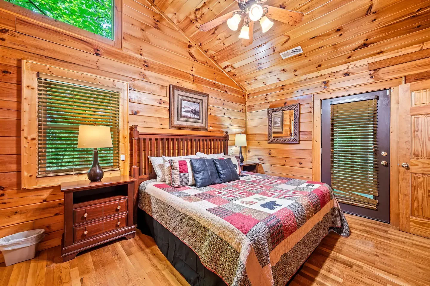 Rustic log cabin bedroom with knotty pine walls, queen bed, and forest views at Forest Creek Retreat Sevierville