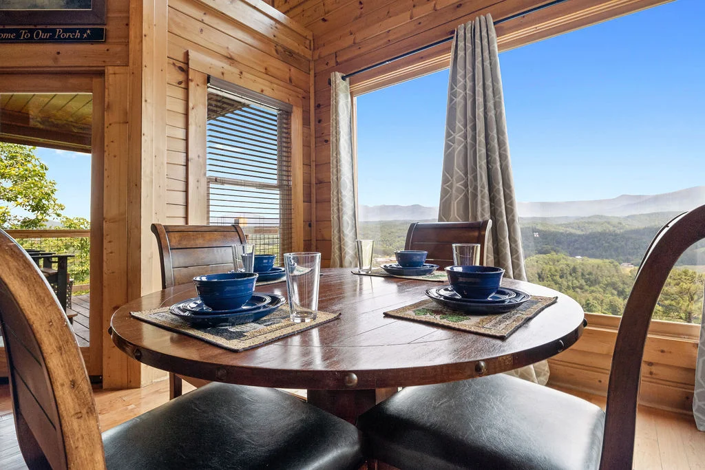 Log cabin dining room with round table, mountain views through large windows in Sevierville
