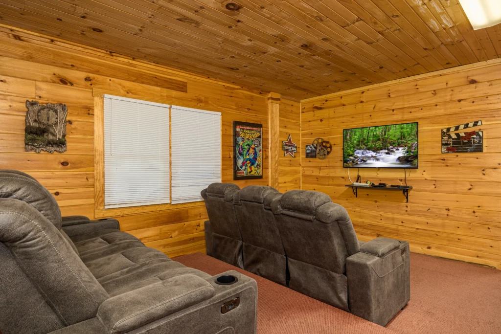 Luxury cabin media room with gray recliners, wood paneling, and wall-mounted TV in Sevierville