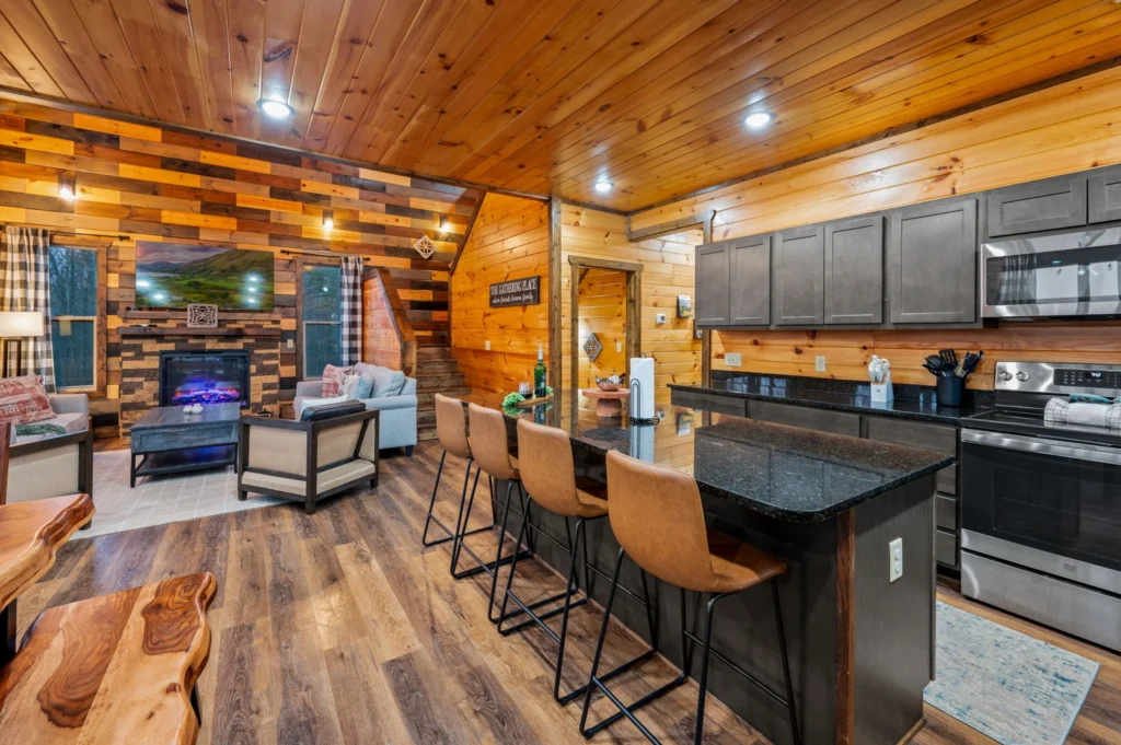 Open-concept log cabin living room with fireplace and modern kitchen in Sevierville