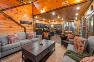 Spacious cabin living room with wood-beamed ceiling, comfortable seating, and equipped kitchen in Gatlinburg TN