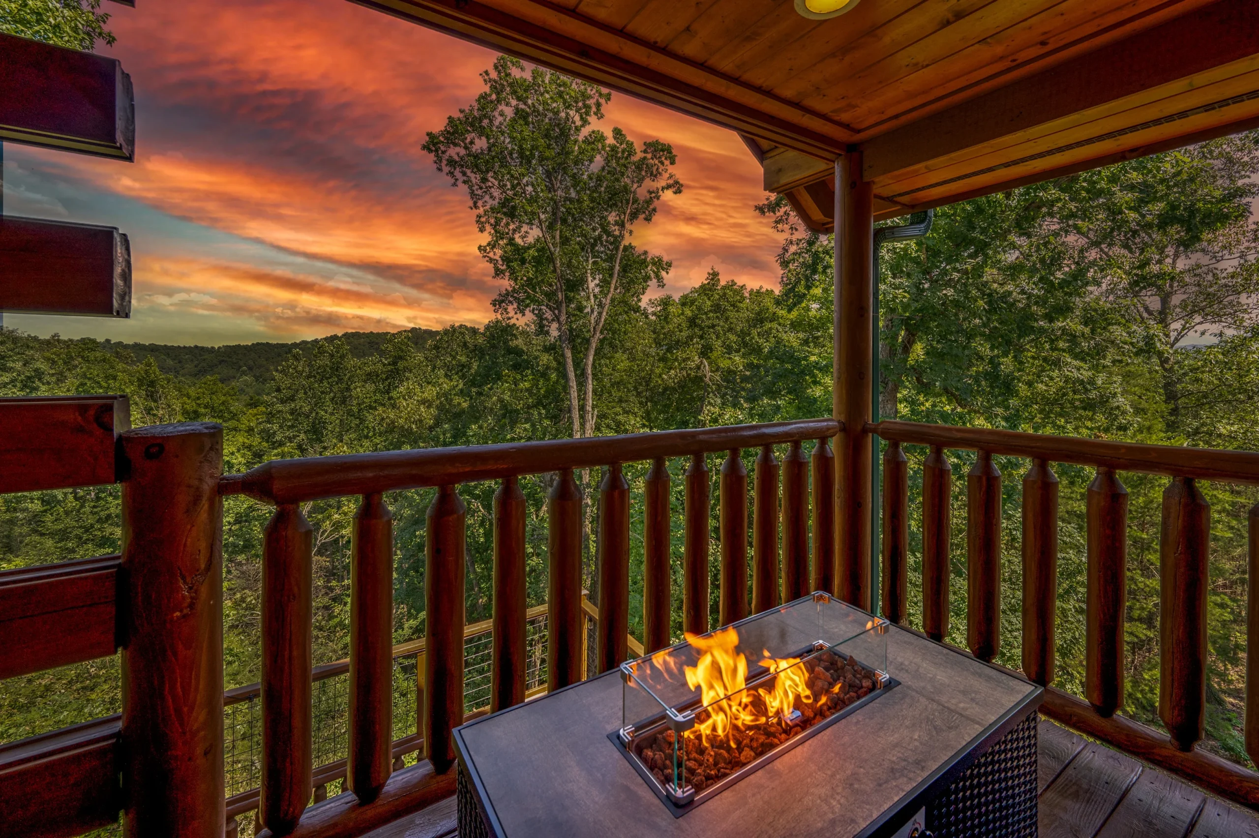 Covered deck with fire pit table overlooking forested Smoky Mountains at sunset near Sevierville TN