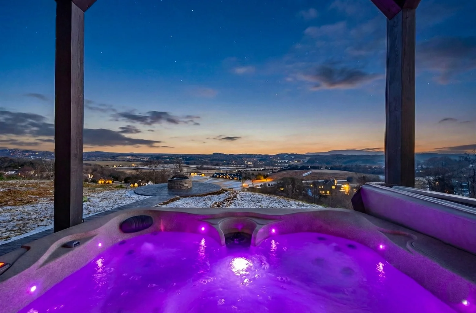 Outdoor deck with hot tub and fire pit overlooking mountain landscape at twilight in Sevierville