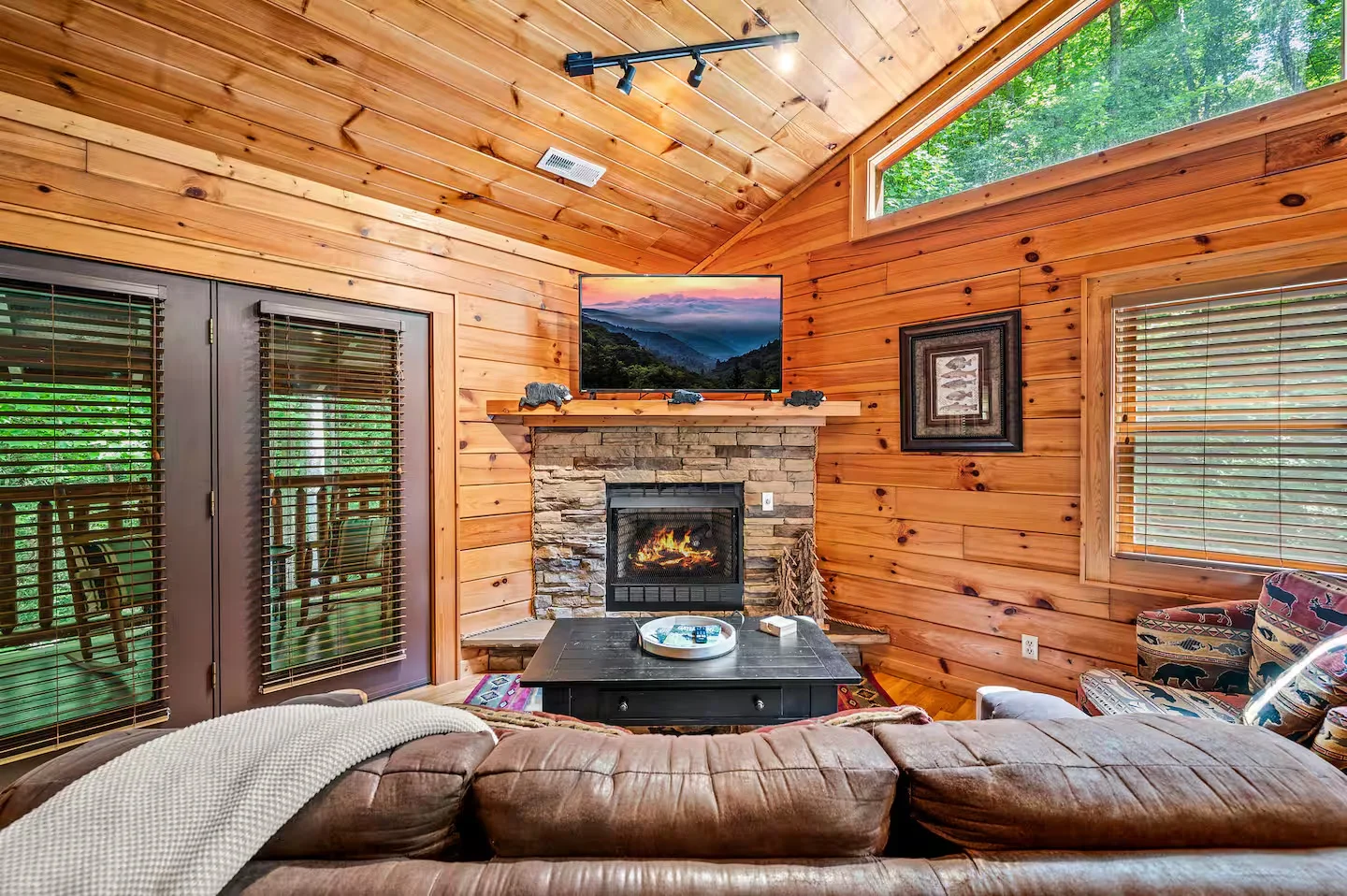Cozy cabin rental living room with stone fireplace and leather sectional in Gatlinburg