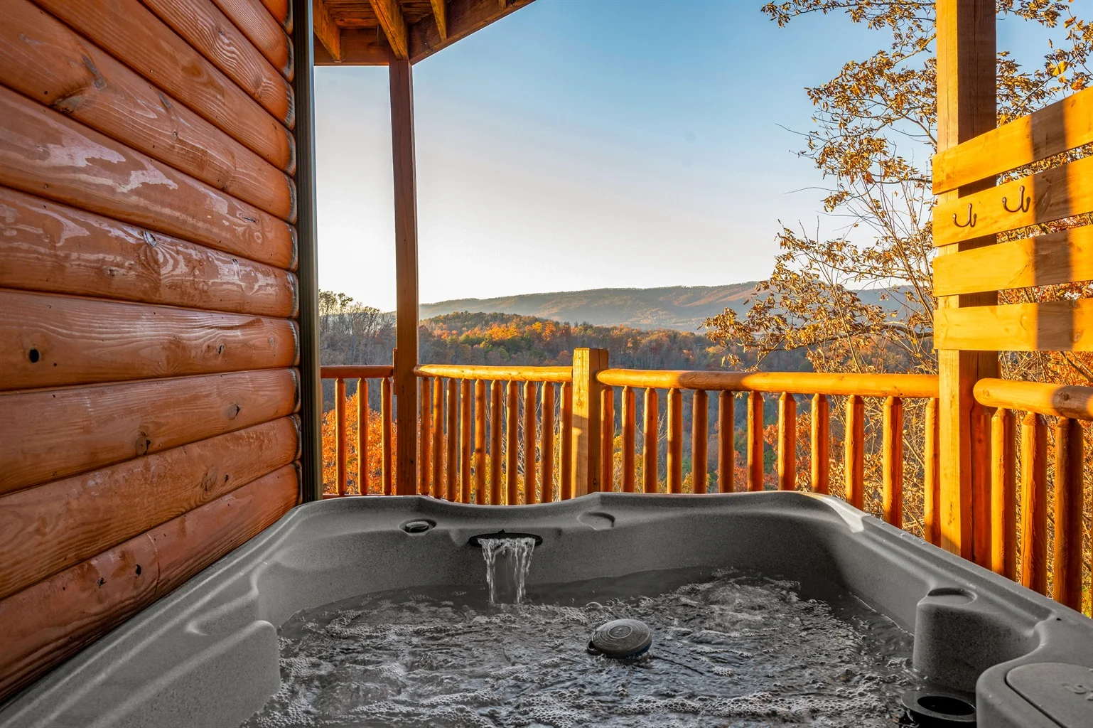 Hot tub on wooden deck with mountain views and fall foliage at Hemlock Hills Cabin Rentals