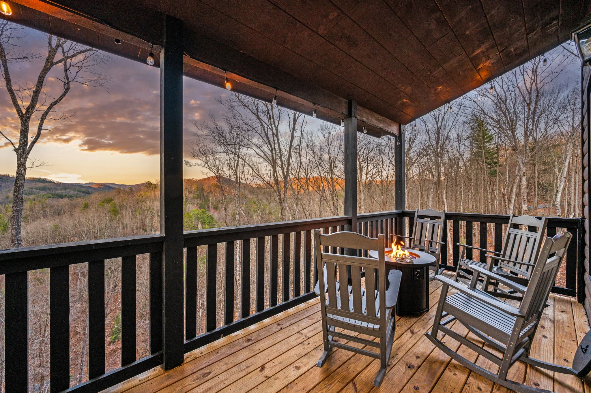 Screened porch with fire table and rocking chairs overlooking forest views in Sevierville cabin