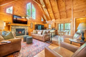 Rustic pet friendly cabin living room with stone fireplace, warm wood interiors, and vaulted ceilings in Pigeon Forge