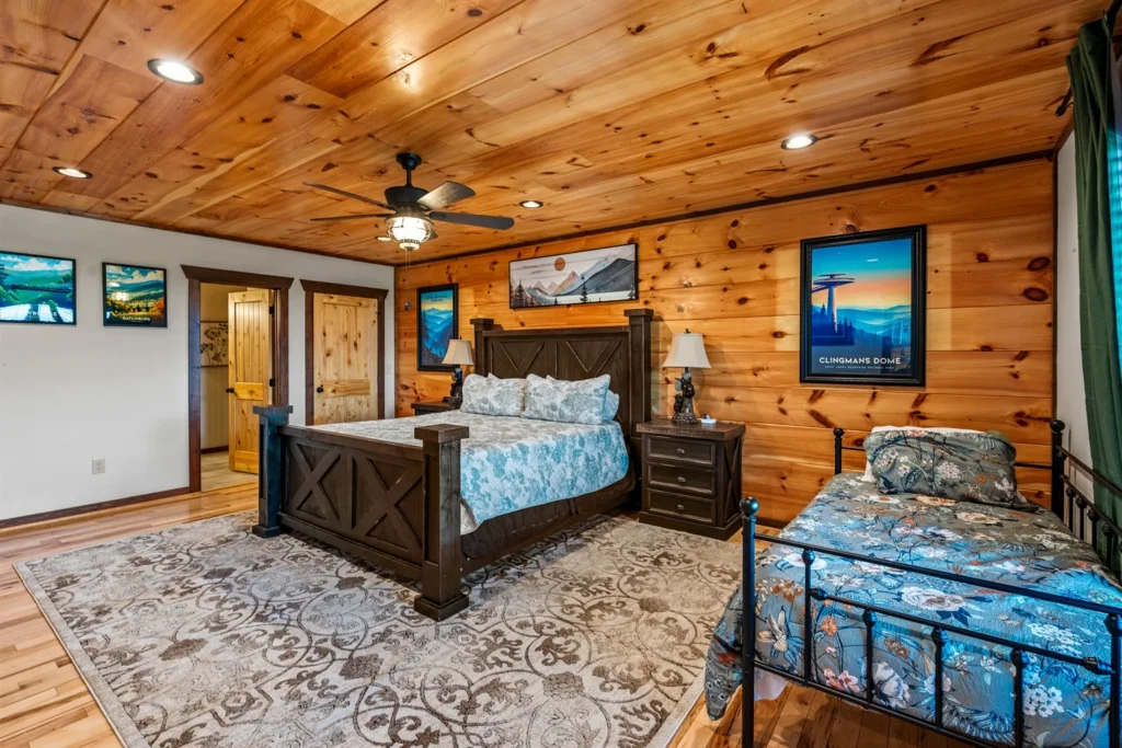 Rustic log cabin bedroom with knotty pine walls, queen bed, and mountain decor in Gatlinburg