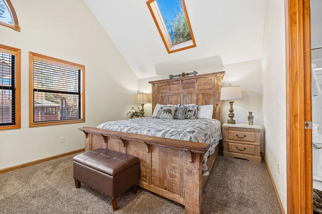 Rustic master bedroom with wooden bed frame, skylights, and mountain views at Hemlock Hills Cabin Rentals in Pigeon Forge