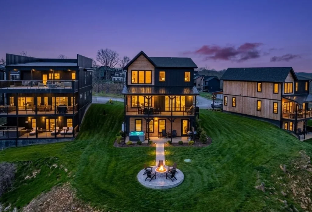 Aerial view of luxury vacation rental Pigeon Forge, TN community at dusk with illuminated homes, fire pit, and mountain views