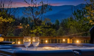 Two wine glasses of sparkling water on a lit hot tub at sunset with mountain views, A Southern Point of View Gatlinburg,