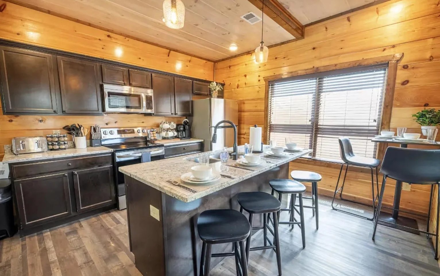 Log cabin kitchen with dark cabinets and granite island with seating in The Marigold, a Pigeon Forge cabin near Bluegrass